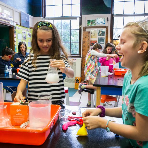 Two girls work on science experiment using beakers