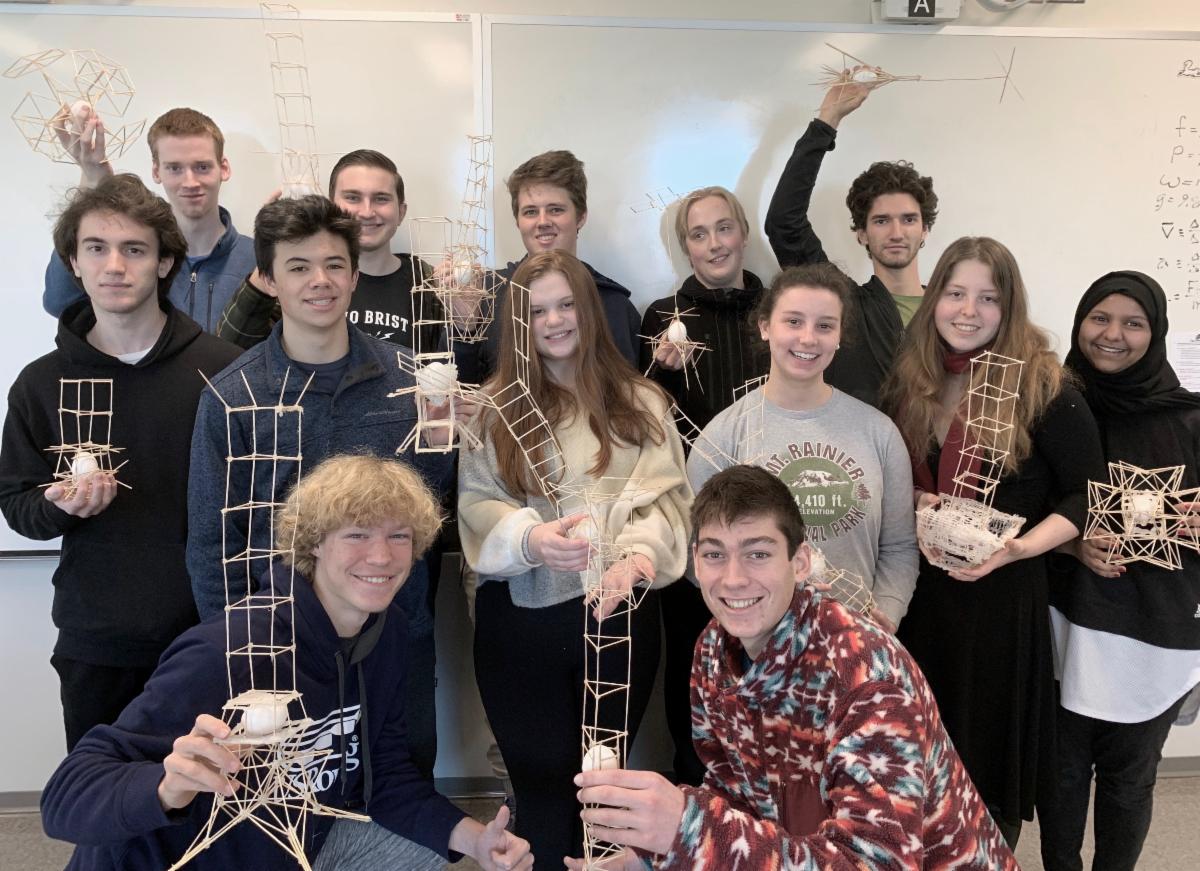 Group of smiling high school students holding up their egg drop apparatus