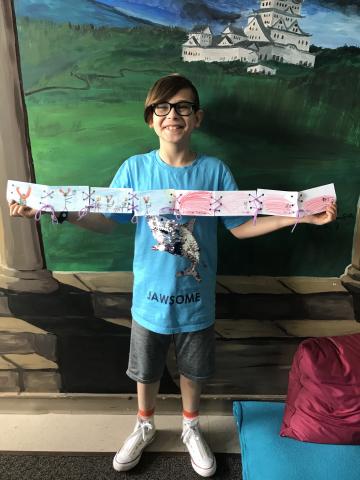 Student smiling and holding unfolded handmade book