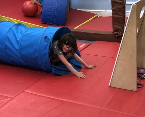 A student pops headfirst out of an occupational therapy tube