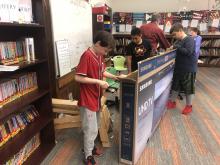 students work together breaking down a cardboard box