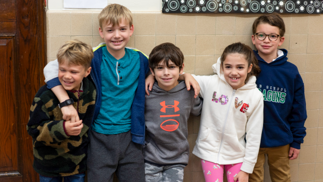 four students pose together in hallway