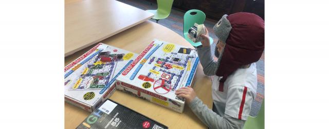 student contemplates board game and life while holding milk and wearing a winter hat